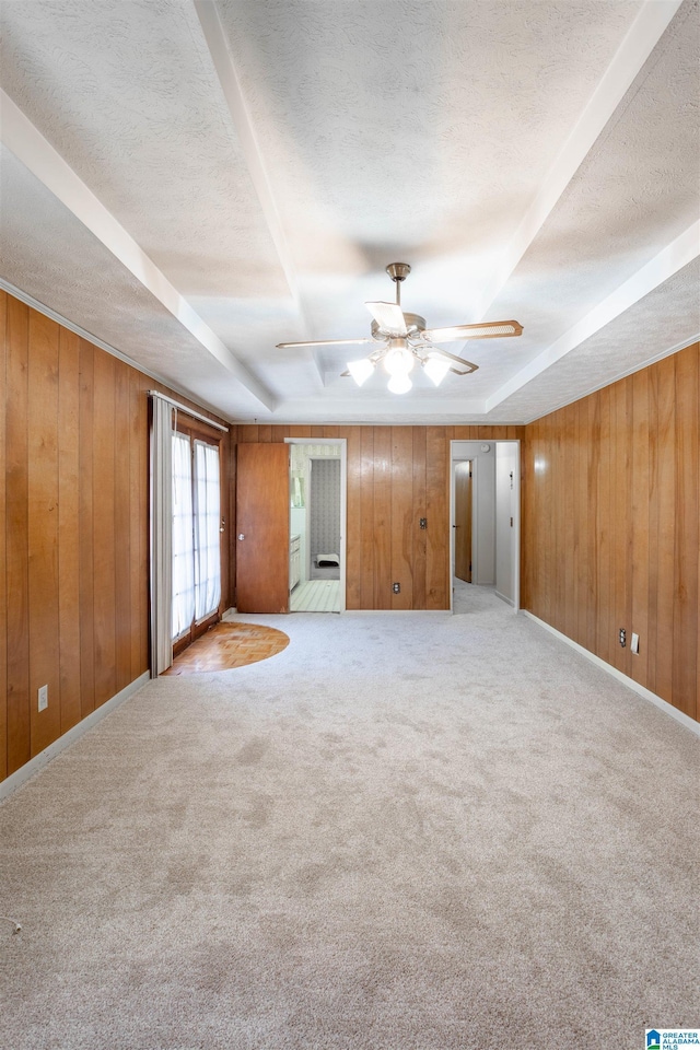 interior space with carpet floors, a textured ceiling, ceiling fan, and wooden walls