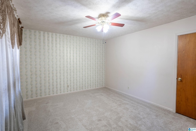 spare room with light carpet, ceiling fan, and a textured ceiling