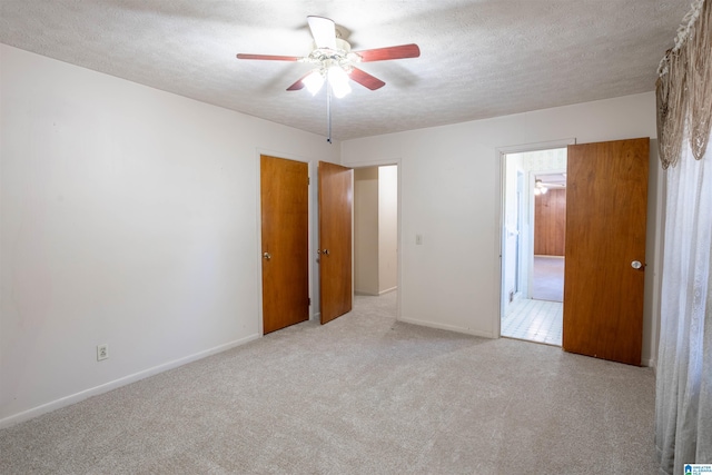 unfurnished bedroom with ceiling fan, light colored carpet, and a textured ceiling