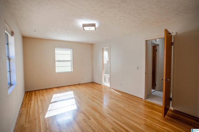 empty room featuring a textured ceiling and light hardwood / wood-style flooring