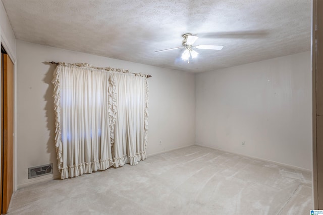 unfurnished room with a textured ceiling, ceiling fan, and carpet flooring