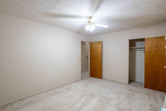 unfurnished bedroom featuring ceiling fan, light colored carpet, a textured ceiling, and a closet