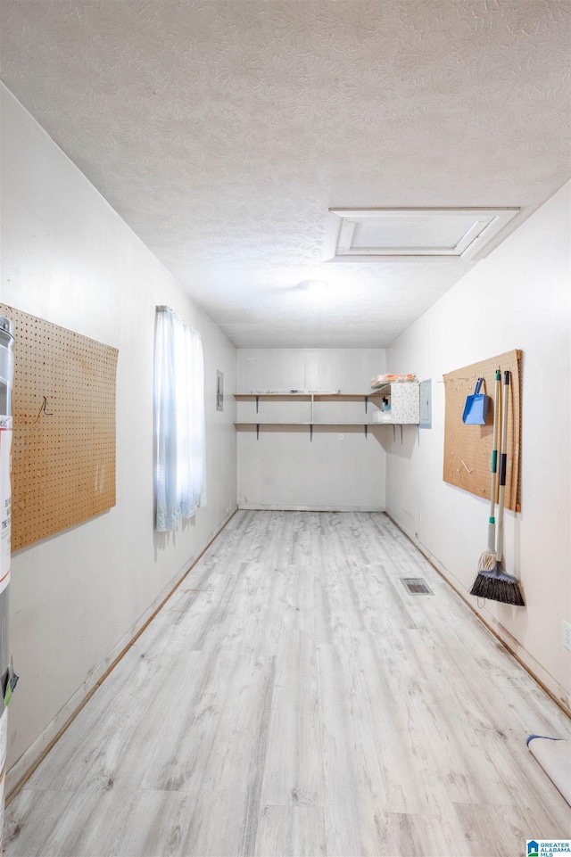 basement featuring a textured ceiling and light hardwood / wood-style flooring