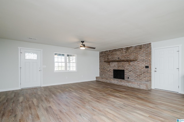 unfurnished living room featuring a fireplace, light hardwood / wood-style flooring, and ceiling fan