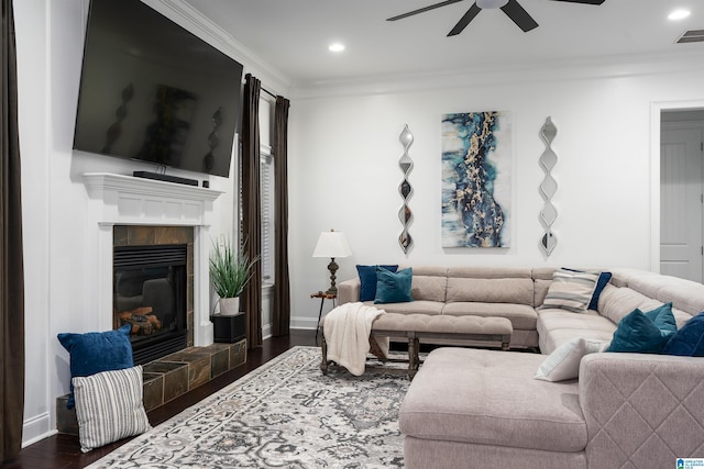 living room featuring dark hardwood / wood-style floors, a tile fireplace, and crown molding