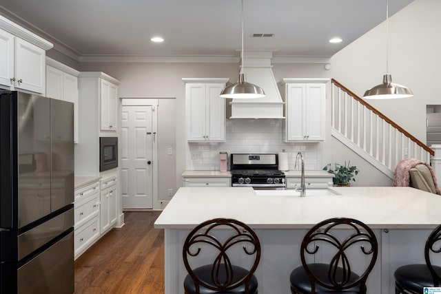 kitchen with hanging light fixtures, appliances with stainless steel finishes, sink, and ornamental molding