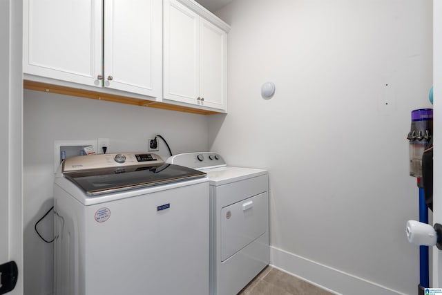 washroom featuring washing machine and dryer, cabinets, and light tile patterned floors