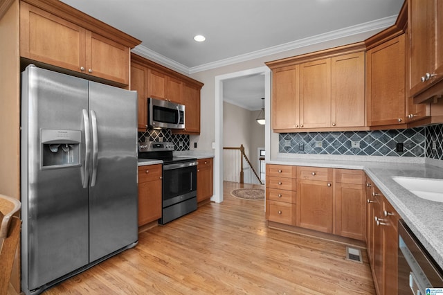 kitchen featuring crown molding, appliances with stainless steel finishes, tasteful backsplash, light stone countertops, and light wood-type flooring