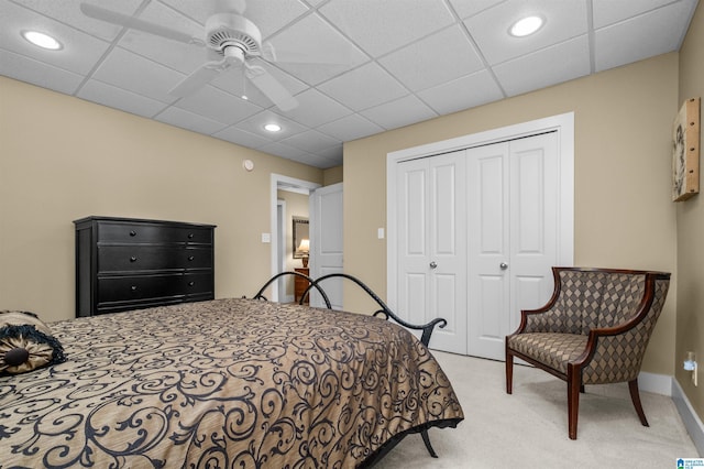 carpeted bedroom featuring a drop ceiling, ceiling fan, and a closet