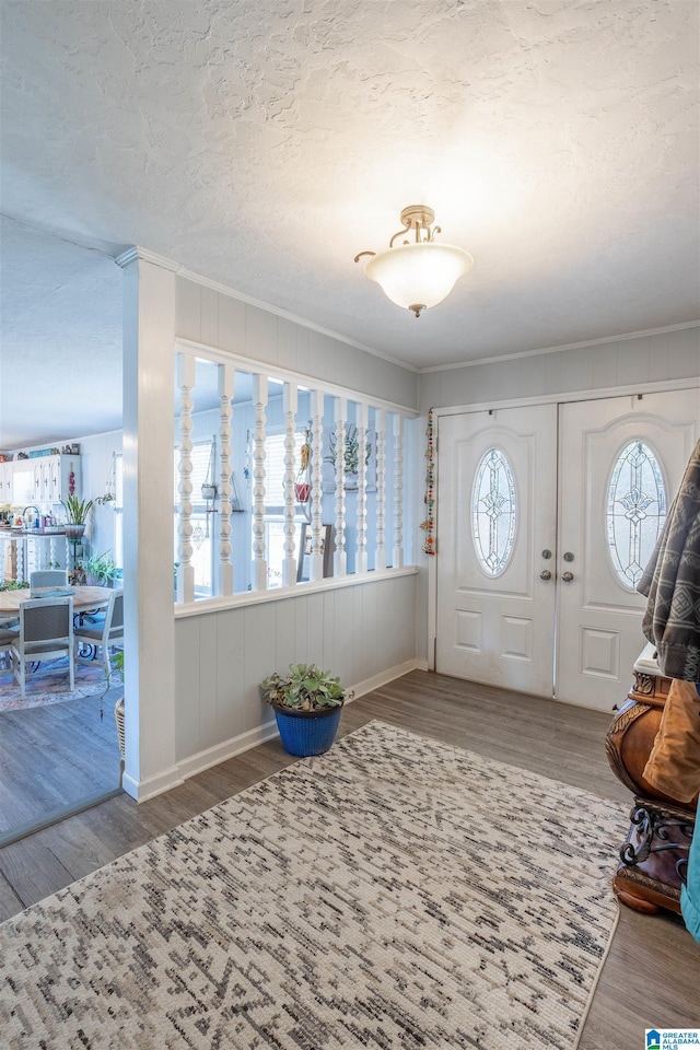 entryway featuring a textured ceiling, ornamental molding, and hardwood / wood-style flooring