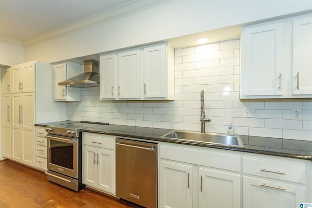 kitchen with white cabinetry, appliances with stainless steel finishes, wall chimney exhaust hood, and tasteful backsplash