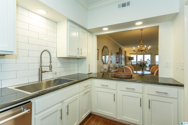 kitchen featuring dishwasher, sink, white cabinets, pendant lighting, and backsplash