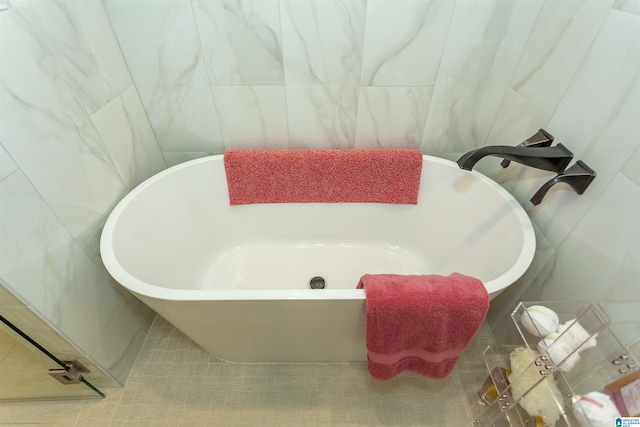 bathroom featuring a bathtub and tile walls