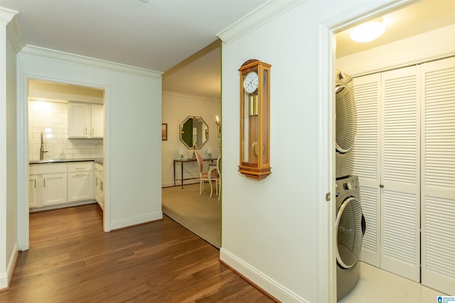 laundry area featuring sink, dark hardwood / wood-style floors, stacked washing maching and dryer, and ornamental molding