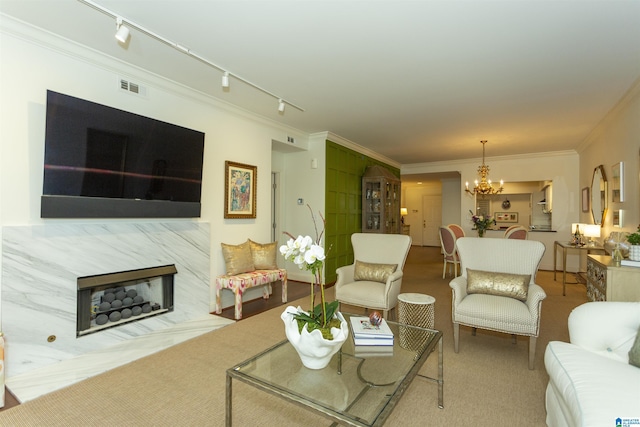 living room with a premium fireplace, carpet floors, ornamental molding, rail lighting, and an inviting chandelier