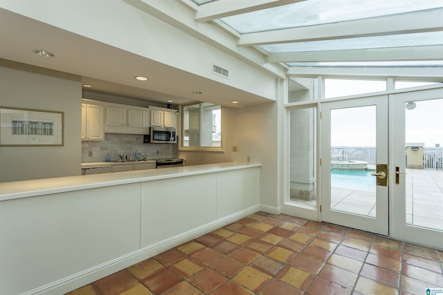 kitchen with appliances with stainless steel finishes, french doors, vaulted ceiling with beams, sink, and backsplash