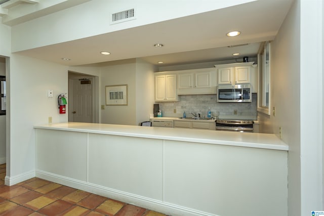 kitchen featuring backsplash, kitchen peninsula, and appliances with stainless steel finishes