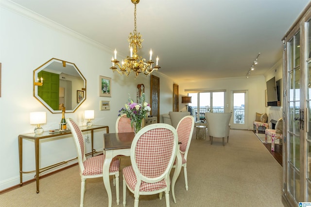 dining room featuring track lighting, light carpet, french doors, ornamental molding, and a chandelier