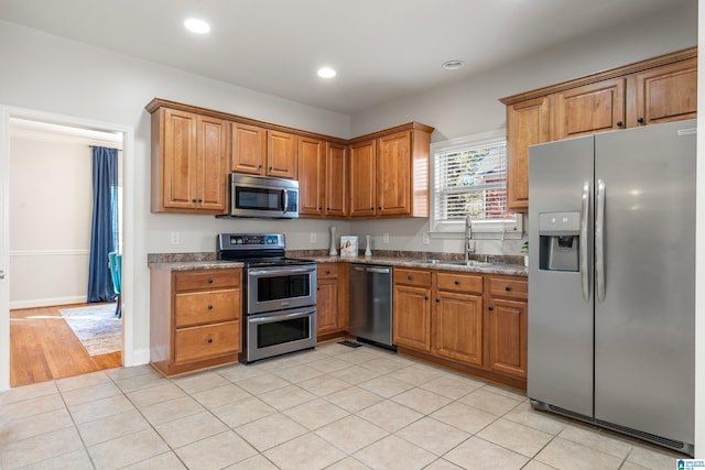 kitchen featuring sink, light stone counters, stainless steel appliances, and light tile patterned flooring