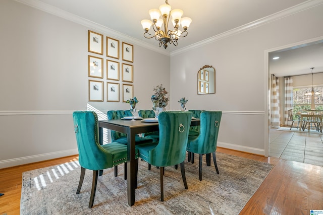 dining area featuring wood-type flooring, ornamental molding, and a notable chandelier