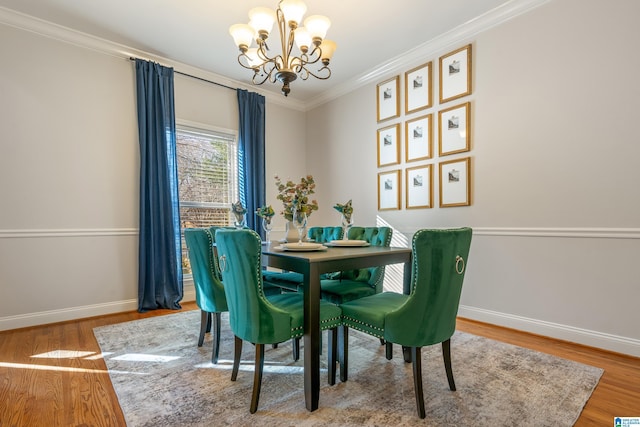 dining room with wood-type flooring, ornamental molding, and a notable chandelier