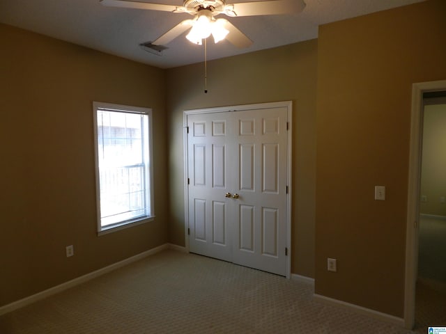 unfurnished bedroom featuring ceiling fan, a closet, and light colored carpet