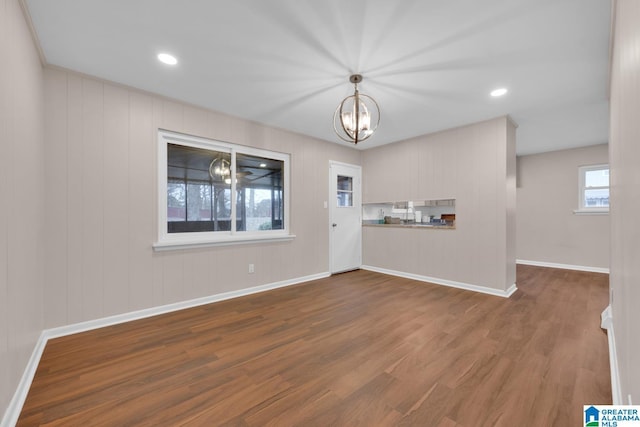 unfurnished living room with wood-type flooring and an inviting chandelier