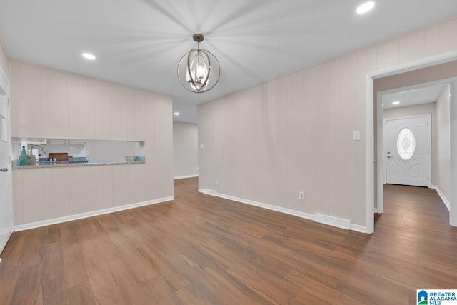 unfurnished living room with sink, a notable chandelier, and dark hardwood / wood-style flooring