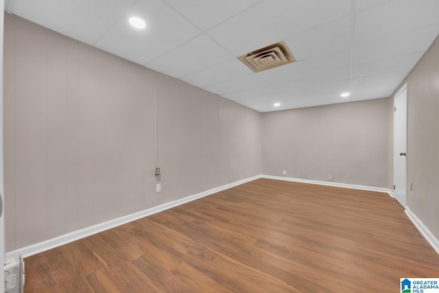 empty room with wood-type flooring and a drop ceiling