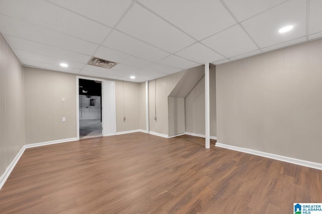 basement with a paneled ceiling and hardwood / wood-style floors