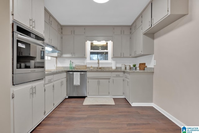 kitchen featuring sink, dark hardwood / wood-style floors, appliances with stainless steel finishes, and light stone counters