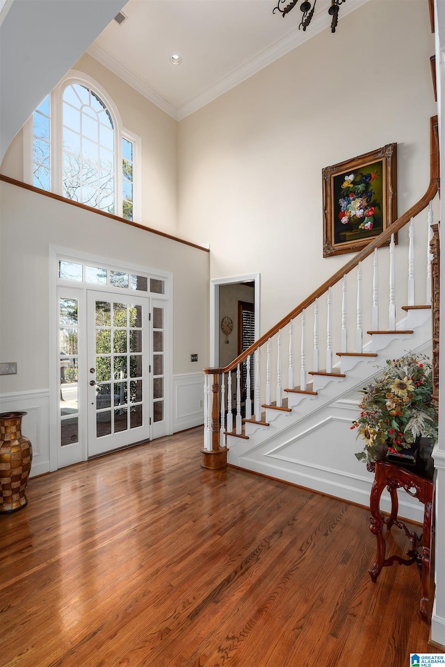 foyer entrance with a towering ceiling, crown molding, and wood-type flooring