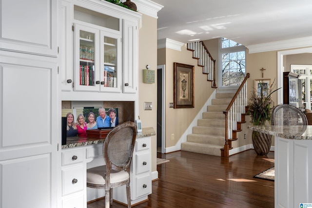 office area featuring built in desk, ornamental molding, and dark hardwood / wood-style flooring