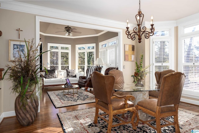 dining space featuring ceiling fan with notable chandelier, dark wood-type flooring, and crown molding