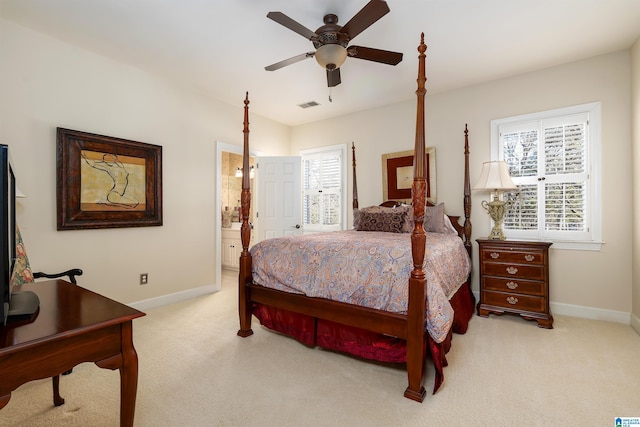 bedroom with ceiling fan, light colored carpet, and ensuite bathroom