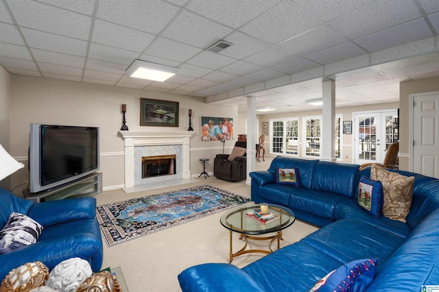 living room featuring a drop ceiling, a premium fireplace, and french doors