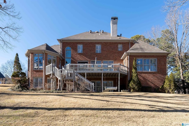 back of property with a deck, a lawn, and a sunroom