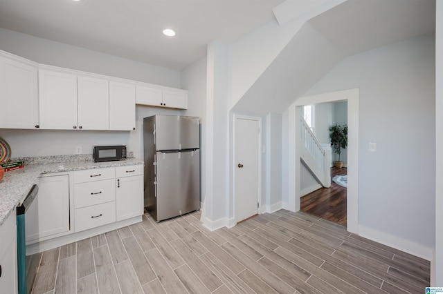 kitchen featuring light hardwood / wood-style floors, white cabinetry, light stone counters, and appliances with stainless steel finishes