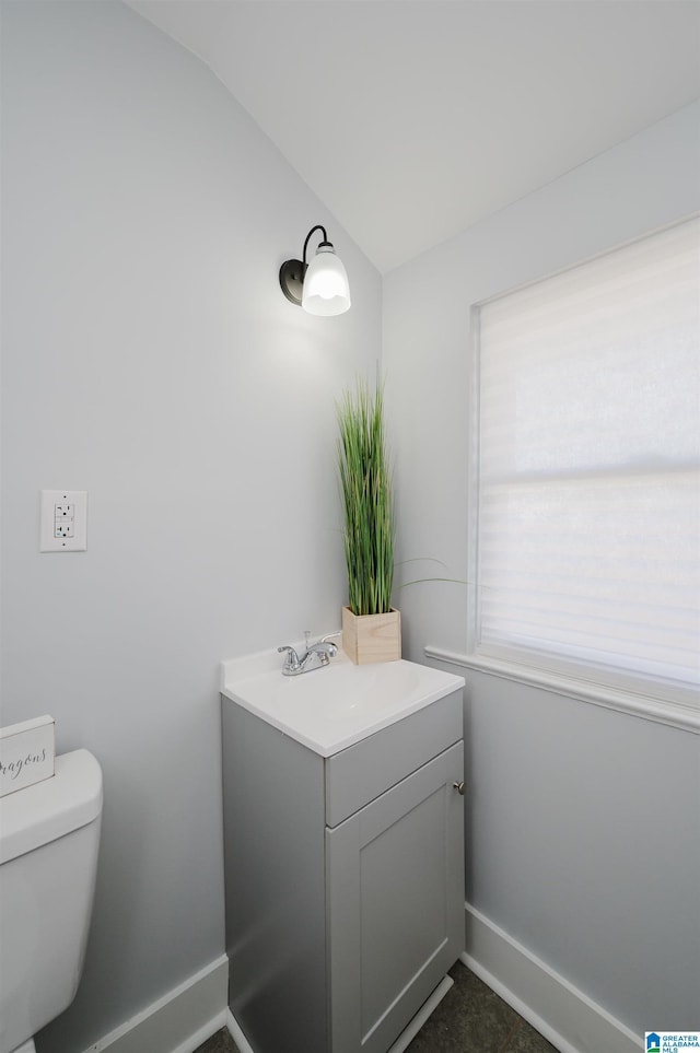 bathroom with vanity, vaulted ceiling, and toilet