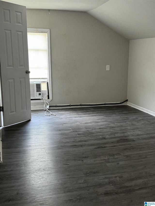 additional living space with cooling unit, dark hardwood / wood-style flooring, and lofted ceiling