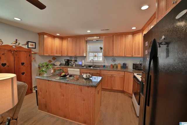 kitchen featuring white appliances, a kitchen island, dark stone countertops, light hardwood / wood-style floors, and sink