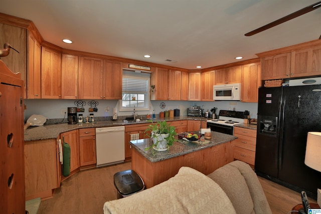 kitchen with light hardwood / wood-style flooring, sink, white appliances, dark stone countertops, and a kitchen island