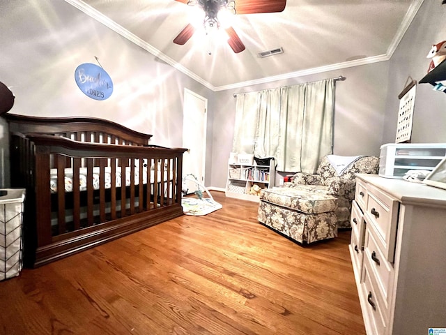 bedroom featuring ceiling fan, ornamental molding, light hardwood / wood-style floors, and a crib