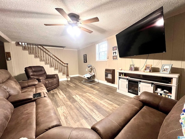 living room with a textured ceiling, ornamental molding, light wood-type flooring, ceiling fan, and heating unit