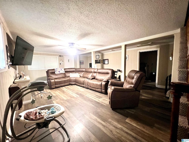 living room with wood-type flooring, a textured ceiling, ceiling fan, and ornamental molding