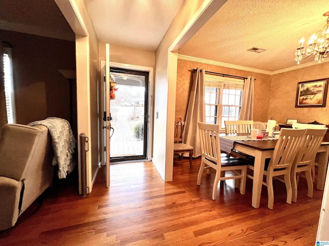 dining room with a notable chandelier, hardwood / wood-style flooring, and a textured ceiling