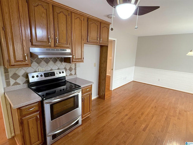 kitchen featuring ceiling fan, light hardwood / wood-style floors, tasteful backsplash, and electric stove