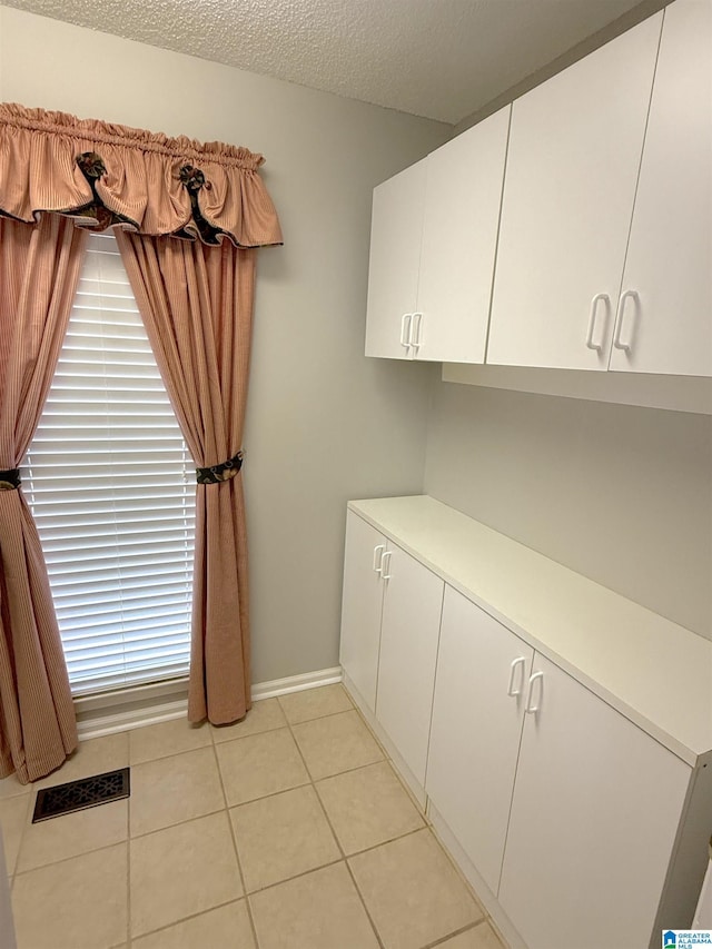 laundry room with a textured ceiling and light tile patterned floors