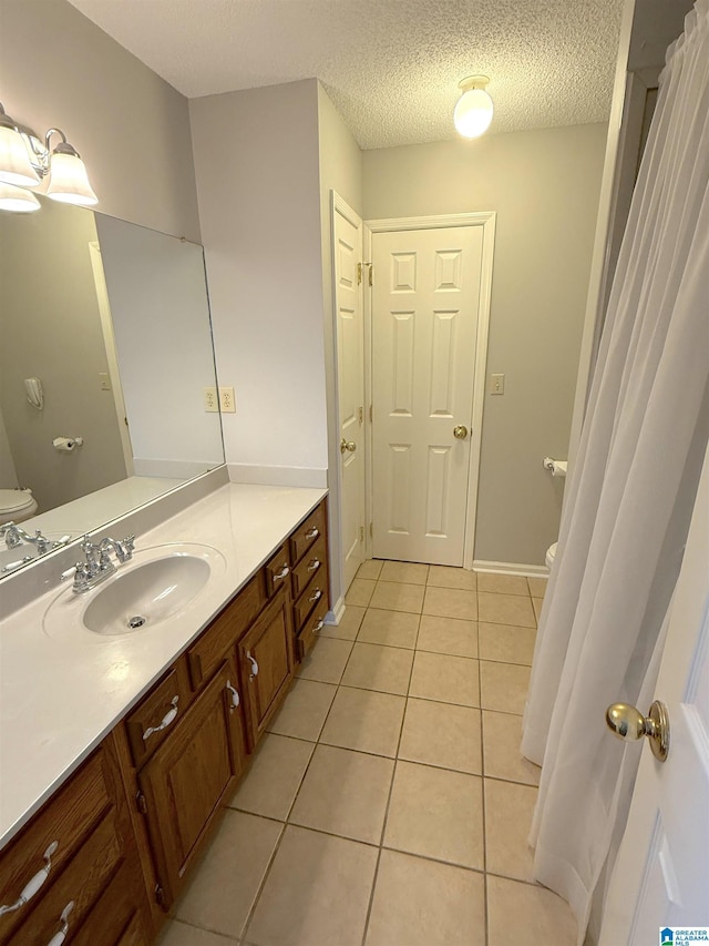 bathroom with a textured ceiling, toilet, tile patterned flooring, and vanity