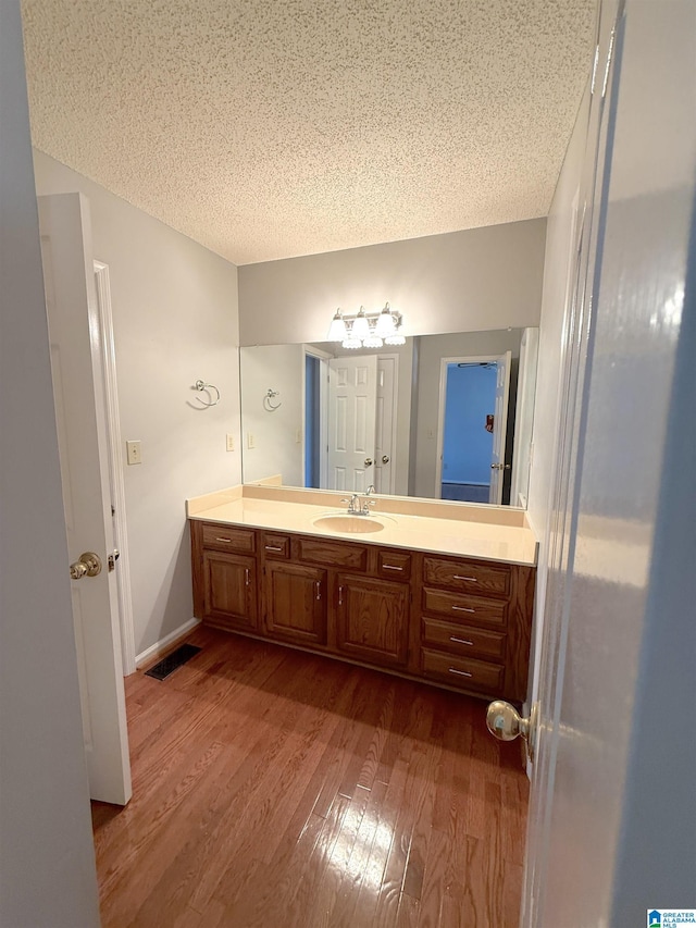 bathroom with wood-type flooring, a textured ceiling, and vanity